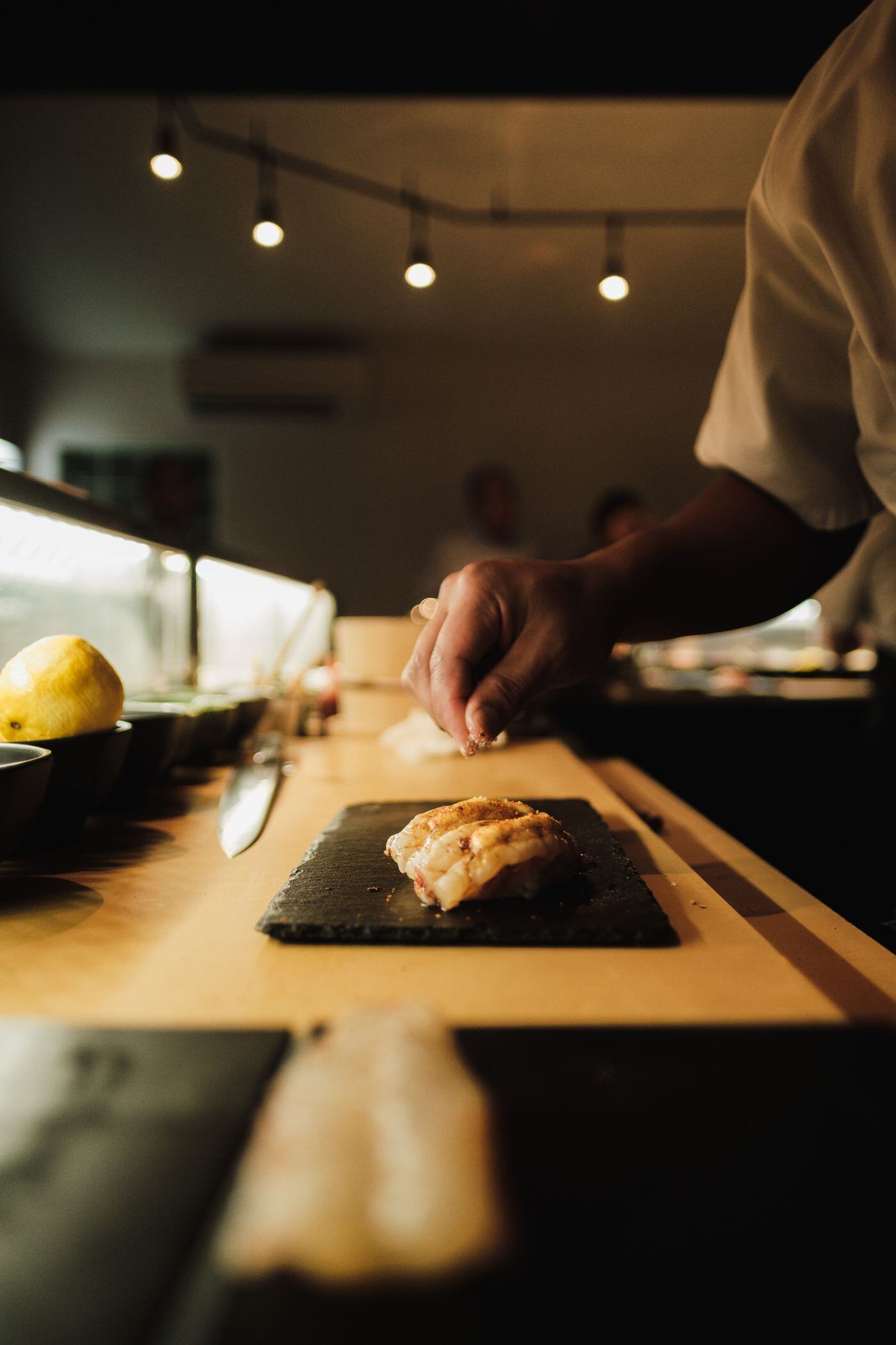 Evening service Sushi chef working at a candlelit live station during an evening event