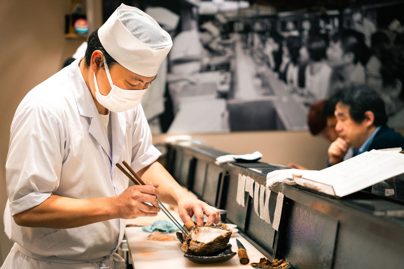 Sushi chef preparing nigiri in front of seated guests at an omakase counter