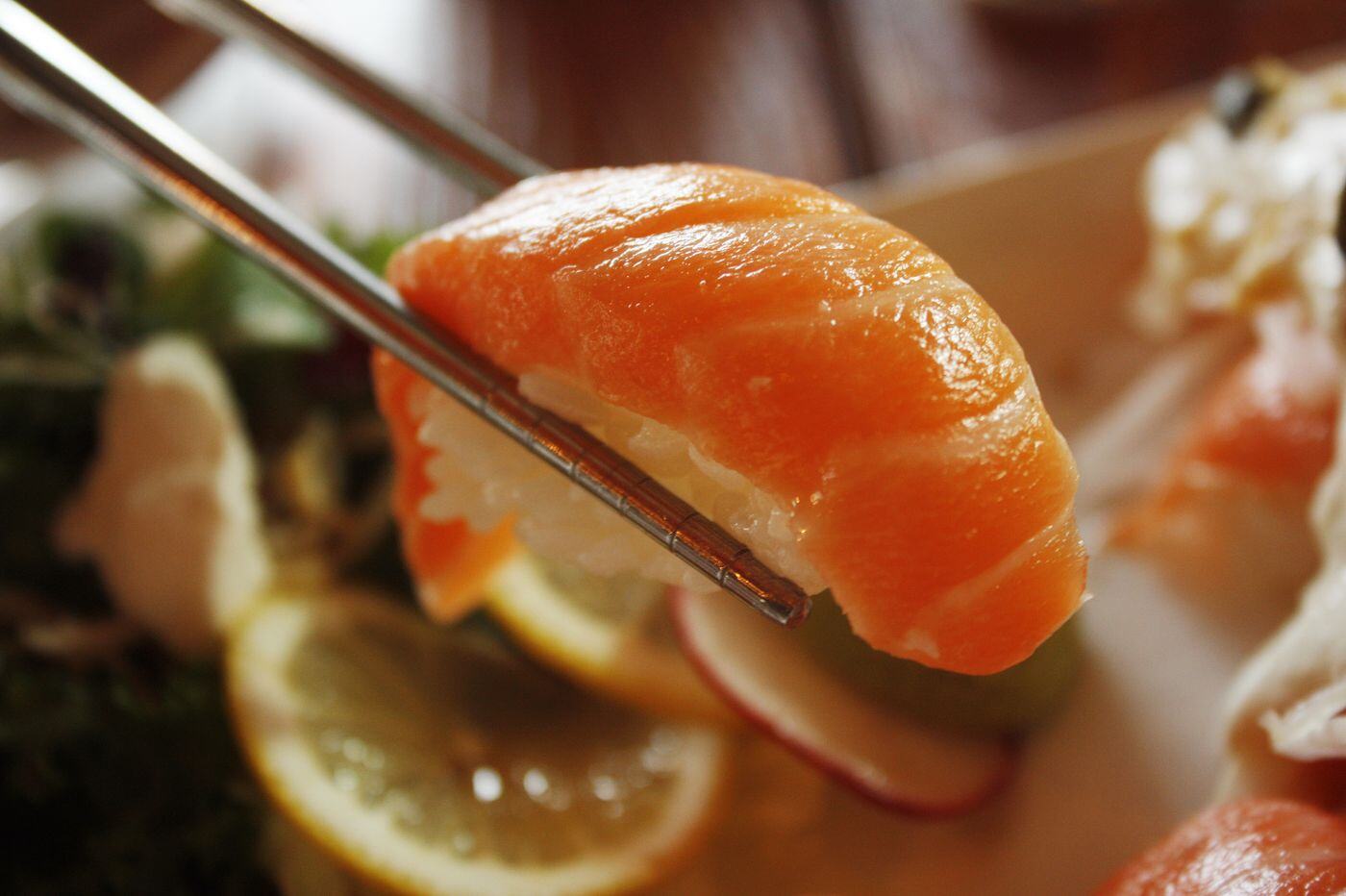 Salmon nigiri held with chopsticks Salmon nigiri held with chopsticks
